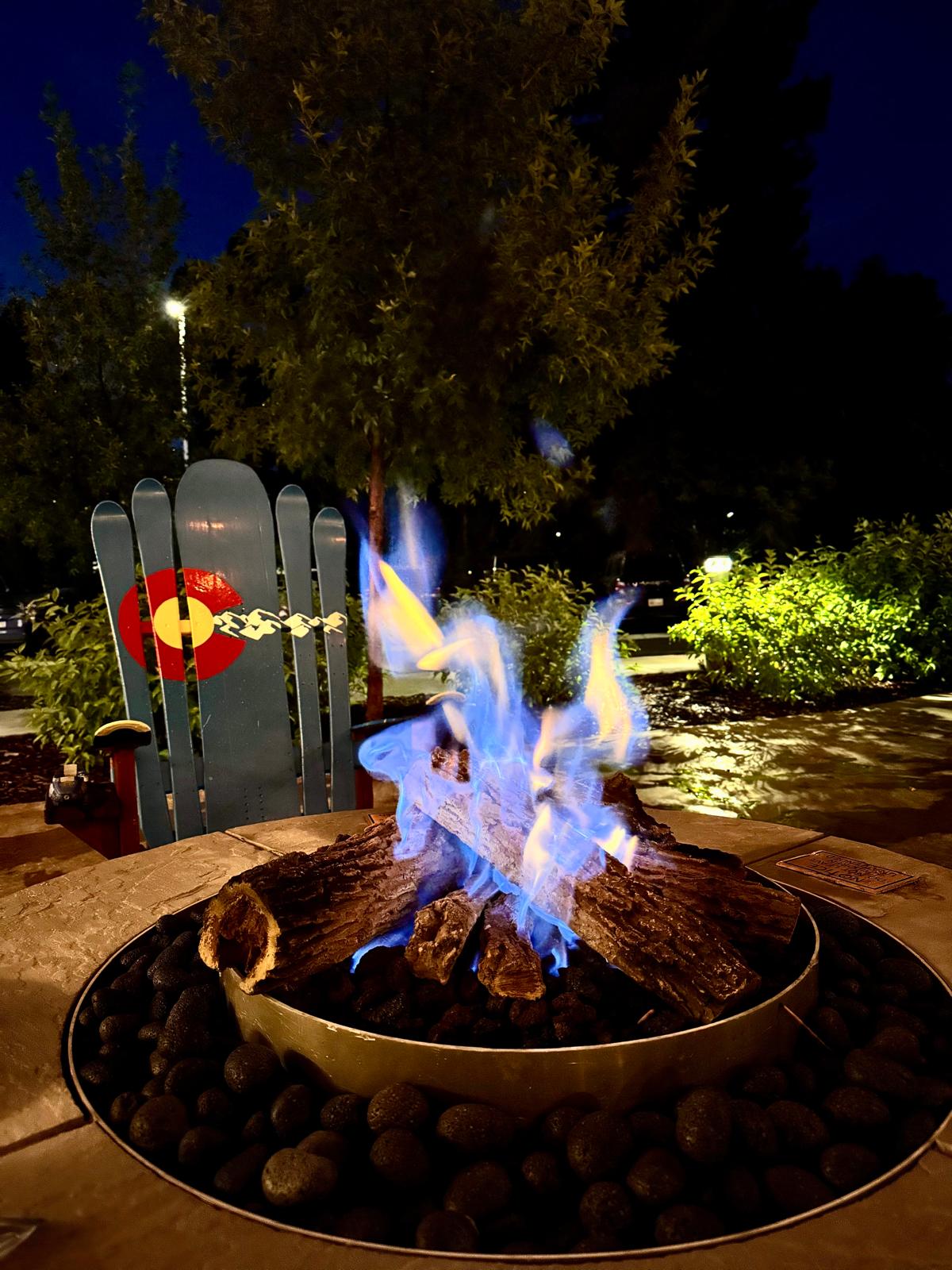 An evening fire beside a chair decorated with the Colorado flag